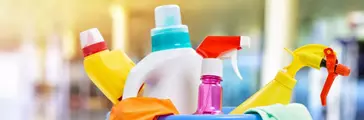 Close up of plastic tub filled with various cleaning supplies