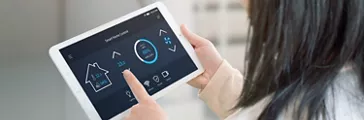 Woman control temperature in living room with smart home control app on tablet. View from the shoulder. Tehnology automation concept.